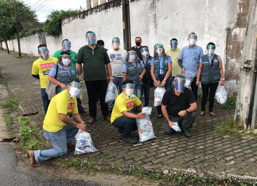 várias pessoas posando para a foto usando máscaras e protetores de rosto